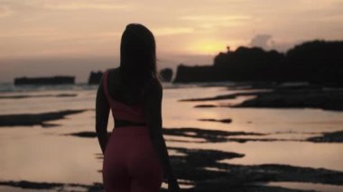 Sahilde gün batımını izleyen genç bir kadın. Yüksek kalite 4k görüntü
