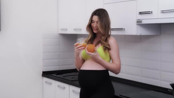 Wesoła Kobieta Ciąży Pijąca Świeży Sok Pomarańczowy Kuchni Przyszłej Mamie — Wideo stockowe