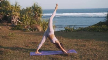 Esnek ve formda bir kadın huzur içinde yoga yapıyor. Atletik kız bacak ve vücut bükümleriyle esneme egzersizi yapıyor. Zindelik ve yogayla formda kalmak. 