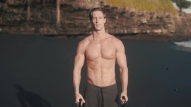 Genç atletik beyaz adam kollarını direniş bandıyla kaldırdı. Mükemmel gövde sporcusu kollarını elastik bant ile sağlığına kavuşturur. Güvenli egzersiz ve güzellik konsepti. Yüksek kalite 4k görüntü