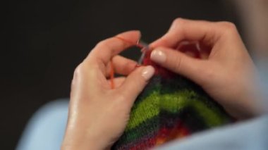 Kadın eli örgü iğneleriyle yün süveter örer. Üst görünüm, yakın çekim eller ve örgü.