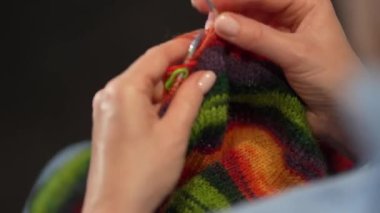 Kadın eli örgü iğneleriyle yün süveter örer. Üst görünüm, yakın çekim eller ve örgü.