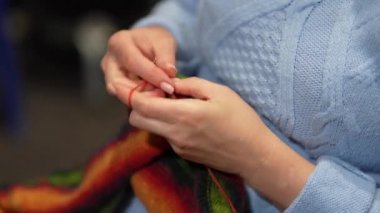 Kadın eli örgü iğneleriyle yün süveter örer. Üst görünüm, yakın çekim eller ve örgü.