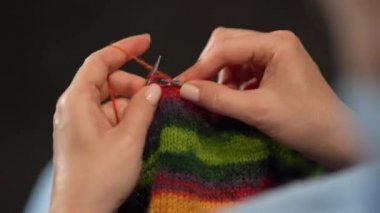 Kadın eli örgü iğneleriyle yün süveter örer. Üst görünüm, yakın çekim eller ve örgü.