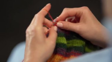 Kadın eli örgü iğneleriyle yün süveter örer. Üst görünüm, yakın çekim eller ve örgü.