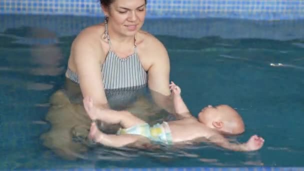 母親はプールで泳いでいる赤ん坊の少年を教えている 赤ちゃんとお母さんはプールで楽しい水泳を持っています — ストック動画