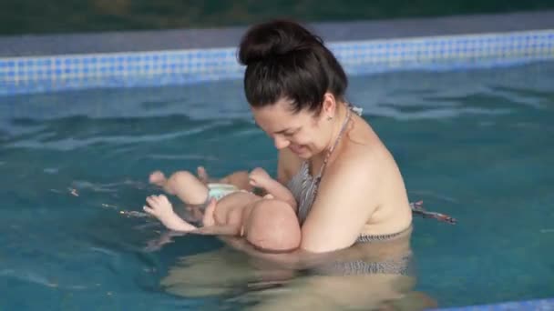 妈妈教男婴在游泳池里游泳 宝宝和妈妈在游泳池里游泳玩得很开心 — 图库视频影像