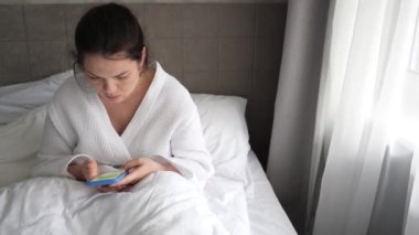 Sabahları genç bir kadın yatakta uzanıyor ve kahve içiyor. Telefondaki mesajlara bakıyor. Kadın uyanır ve evinde bir bardak sıcak içecekle akıllı telefonuna bakar..