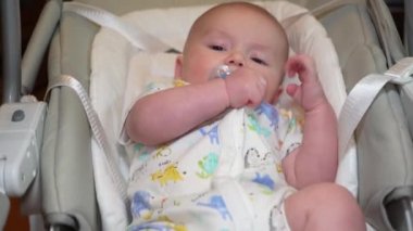 Elektronik salıncakta sallanan bir bebek, elektrikli sandalyede yatan şirin bir bebek. Çocuk gelişimi ve çocukluk.