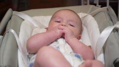 Elektronik salıncakta sallanan bir bebek, elektrikli sandalyede yatan şirin bir bebek. Çocuk gelişimi ve çocukluk.