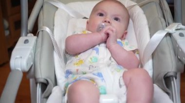 Elektronik salıncakta sallanan bir bebek, elektrikli sandalyede yatan şirin bir bebek. Çocuk gelişimi ve çocukluk.