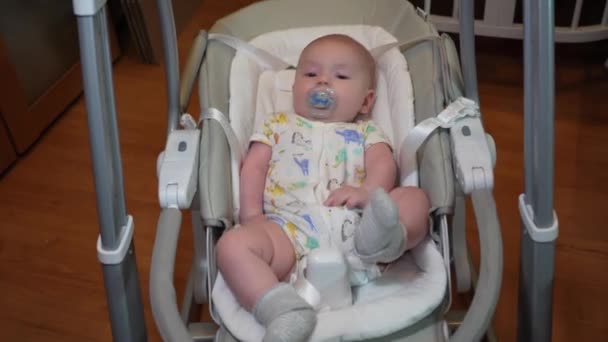 Baby schaukelt in einer elektronischen Schaukel, Netter kleiner Junge liegt in einem elektrischen Schaukelstuhl. Kindliche Entwicklung und Kindheit. — Stockvideo