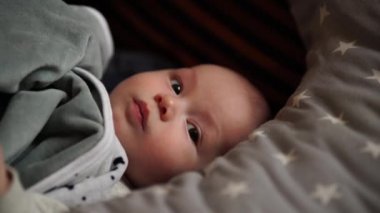 Bebek evde bir yatakta oynuyor. Bebek yatakta yatıyor.