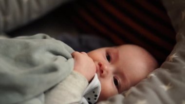 Bebek evde bir yatakta oynuyor. Bebek yatakta yatıyor.