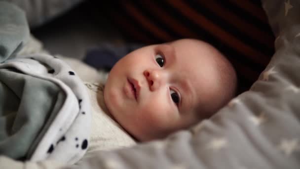 Kleine jongen die thuis op een bed speelt. Baby speelt liggend in bed — Stockvideo