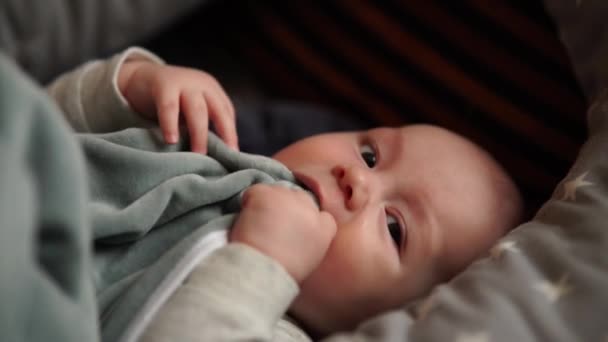 A kisfiú az ágyon játszik otthon. A baba az ágyban fekszik. — Stock videók