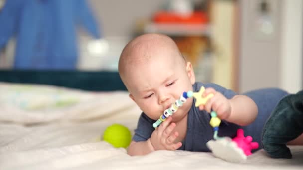 5ヶ月活動中の赤ちゃんのおもちゃに触れる。幼児男の子遊びますおもちゃを開発します上に横たわるソファ. — ストック動画