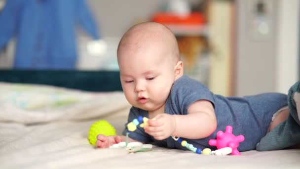 Jouets actifs pour bébé de 5 mois. Bébé garçon bébé jouant avec des jouets en développement couché sur le canapé. — Video