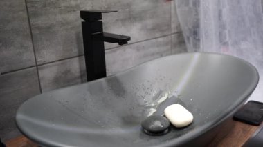 Kolunda dövme olan bir adam ellerini sabunla yıkıyor.