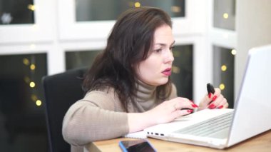 Workplace of freelance worker at home office. Young woman works using computer and other devices. Remote job concept.