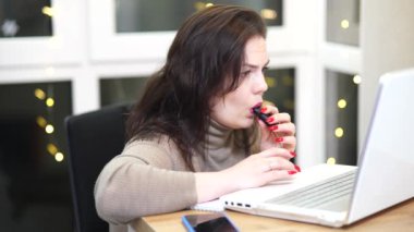 Workplace of freelance worker at home office. Young woman works using computer and other devices. Remote job concept.