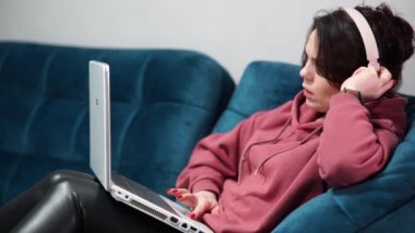 İnternetteki iş toplantısında kulaklıkla konuşan bir kız. Evde uzaktan çalışan, günlük giysiler içinde serbest çalışan bir kadın..