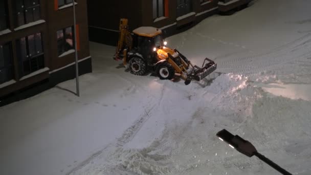 Moskwa, Rosja - 27 stycznia 2022 r.: Specjalny sprzęt czyści śnieg na podwórzu domu, wiadro buldożera usuwa śnieg. — Wideo stockowe