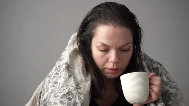病累妇女白杯患者坐在沙发上与偏头痛病毒症状作斗争喝热茶热的画像 — 图库视频影像
