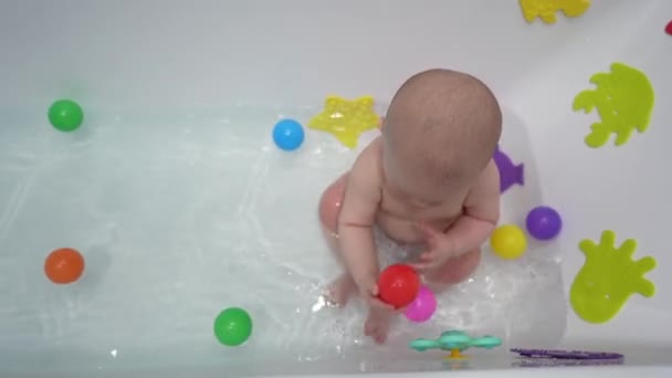 可爱的小男孩带着玩具在白色的浴室里洗澡 — 图库视频影像