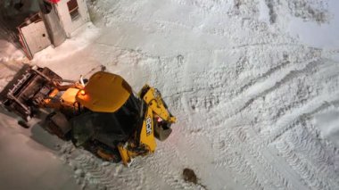 Moskova, Rusya - 10 Şubat 2022: Kazıyıcı kovayla traktör yoldan kar yığınlarını alıyor. Şehir ortamında buldozer kovayla karı temizler..