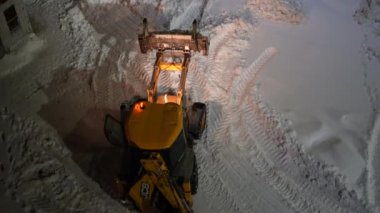 Moskova, Rusya - 10 Şubat 2022: Kazıyıcı kovayla traktör yoldan kar yığınlarını alıyor. Şehir ortamında buldozer kovayla karı temizler..