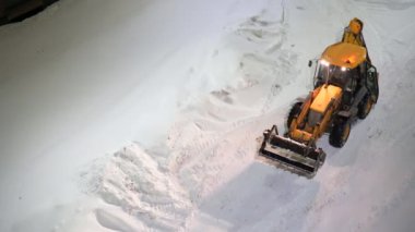 Moskova, Rusya - 10 Şubat 2022: Kazıyıcı kovayla traktör yoldan kar yığınlarını alıyor. Şehir ortamında buldozer kovayla karı temizler..