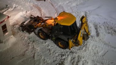 Moskova, Rusya - 10 Şubat 2022: Kazıyıcı kovayla traktör yoldan kar yığınlarını alıyor. Şehir ortamında buldozer kovayla karı temizler..