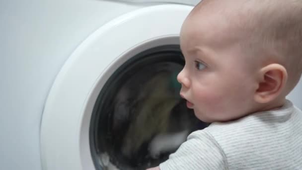 可愛い男の子が洗濯機の中を見ている 子供は洗濯機を調べている — ストック動画