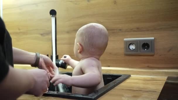 Bébé dans l'évier de cuisine se baigner et jouer avec l'eau. — Video