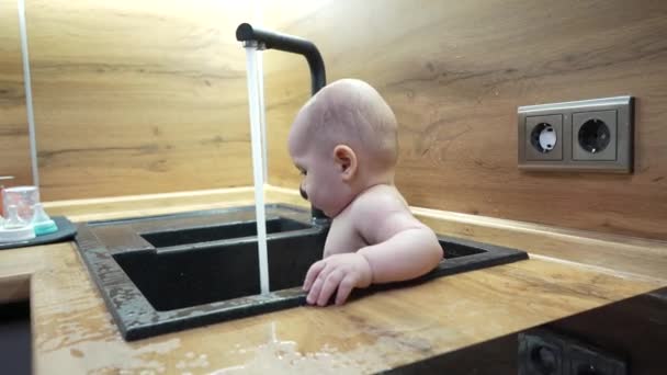 Baby in de keuken wastafel baden en spelen met water. — Stockvideo