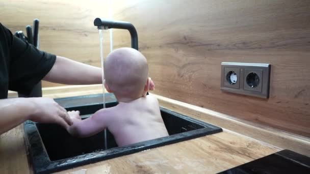 Bebê na pia da cozinha tomar banho e brincar com água. — Vídeo de Stock