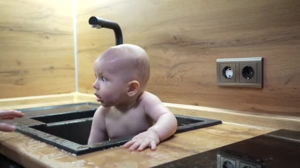 Ребенок на кухне тонет в ванне и играет с водой. — стоковое видео