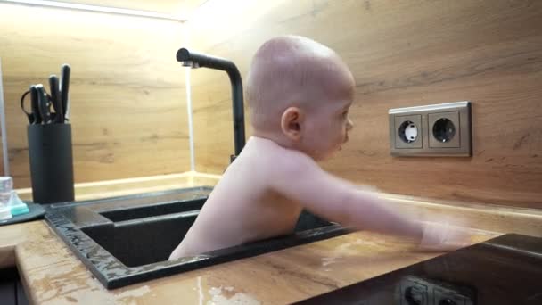 Μωρό στην κουζίνα νεροχύτη μπάνιο και παίζει με το νερό. — Αρχείο Βίντεο