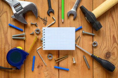 Ahşap zeminde rastgele saçılmış bir sürü inşaat aleti, vida ve panel var. Ortasında notunuzu eklemek için boş karalanmış bir defter var..