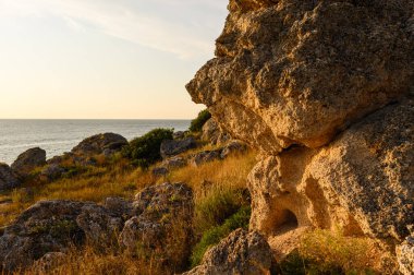 Gün batımında kayalık bir sahilde büyük taşlar. Kırım 'da akşam manzarası