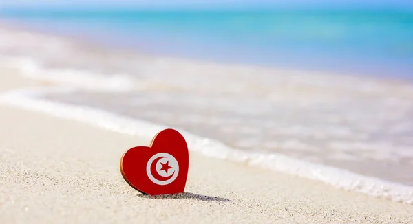 Tunus bayrağı kumlu bir sahilde kalp şeklinde. Tunus 'taki en iyi tatil kavramı