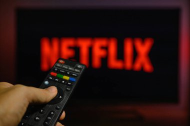 Vladimir, Rusya - Kasım 2021: Netflix ekran koruyuculu bir televizyonun arka planında siyah bir uzaktan kumandayla. Uzaktan kumandalı ele odaklan.