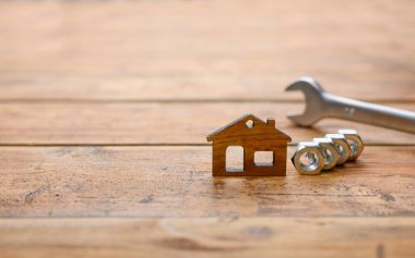 Cevizlerin yanında küçük bir ev ve ahşap bir arka planda İngiliz anahtarı. Ev yenileme konsepti. Eve odaklan..