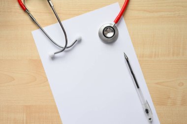 Kalem ve steteskopla beyaz, boş bir kağıdın üst görüntüsü. Klinikte tıbbi teşhis konsepti.