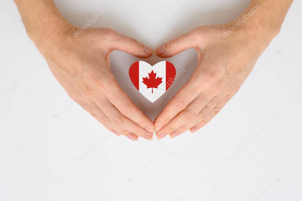The national flag of Canada in human hands. The concept of patriotism, respect and solidarity with the citizens of Canada.