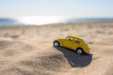 Anapa, Rusya - Temmuz 2021: Kumsalda sarı oyuncak araba. Bir araba off-road kullanıyor.