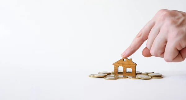 Man Hand Points Figurine Wooden House Pile Coins White Background — Stockfoto