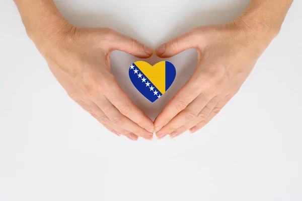 The national flag of Bosnia and Herzegovina in female hands. View from above