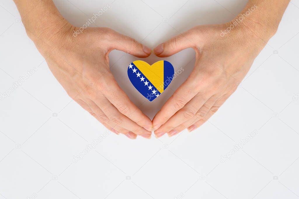 The national flag of Bosnia and Herzegovina in female hands. View from above